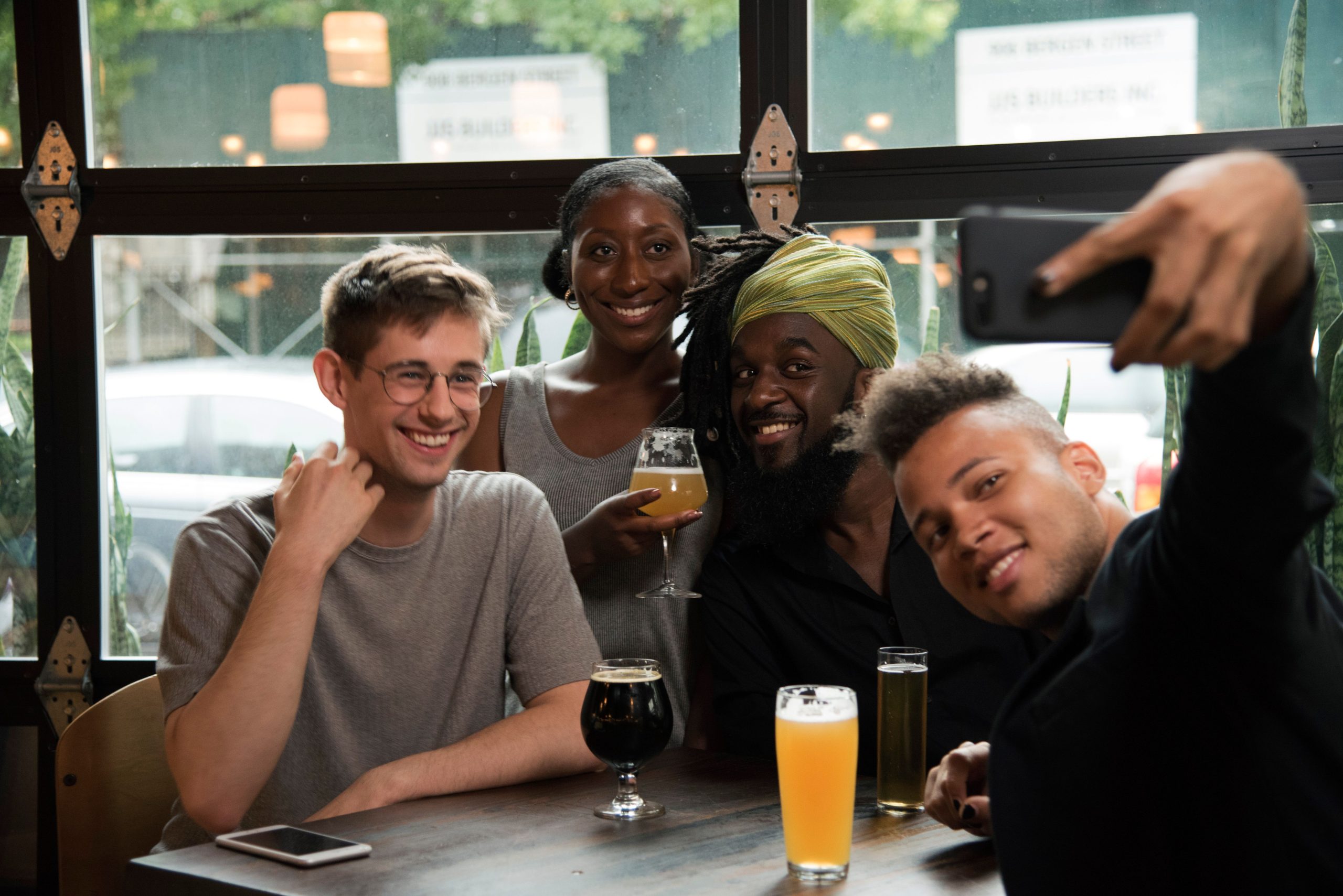 Quatro amigos tiram uma selfie enquanto bebem cervejas de estilos diferentes