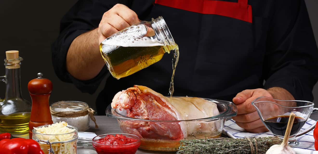 Imagem de um homem colocando cerveja numa peça de carne para marinar