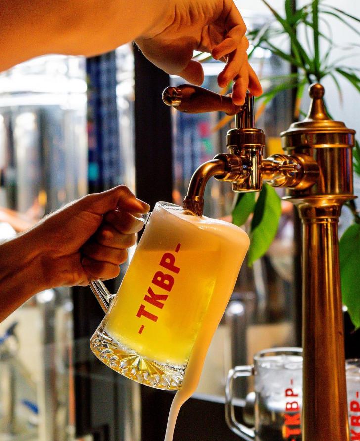 Foto de uma mão servindo cerveja na caneca do tank brewpub