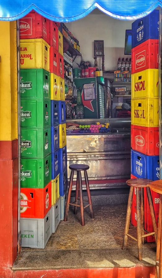 Imagem de um butiquim de entrada estreita, repleta de garrafas empilhadas. imagem super colorida pelos diferentes rotulos