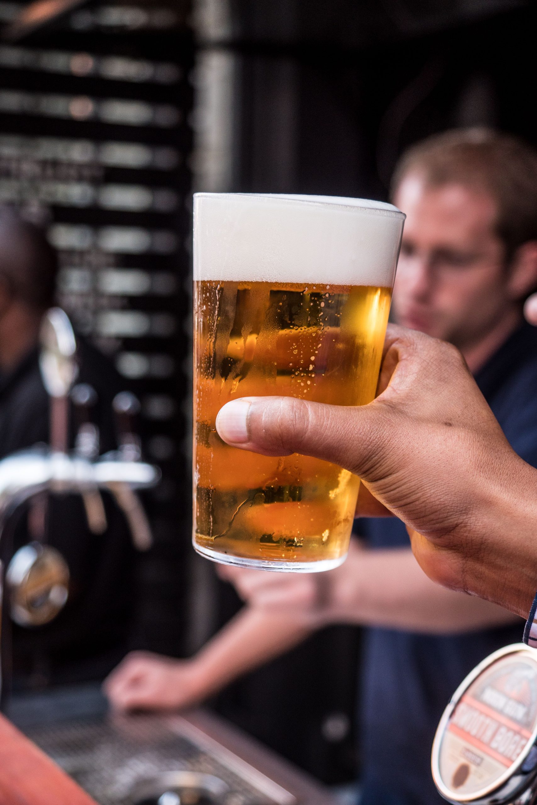foto de uma mão segurando um pint de cerveja