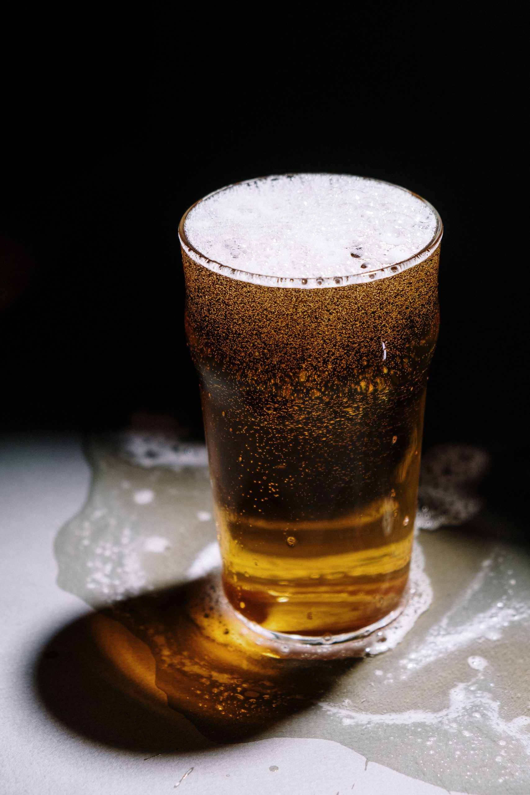 Pint de cerveja clara com pouca espuma em uma mesa