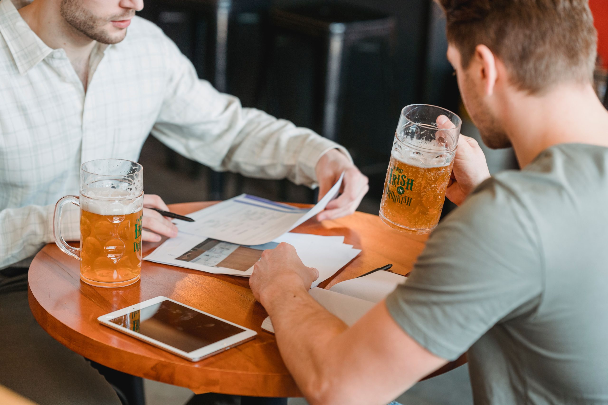 Dois homens bebendo e fazendo anotações em uma mesa