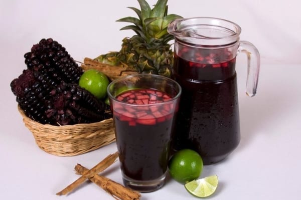 foto de jarra de titia morada e um copo servido com pedaços de abacaxi. 