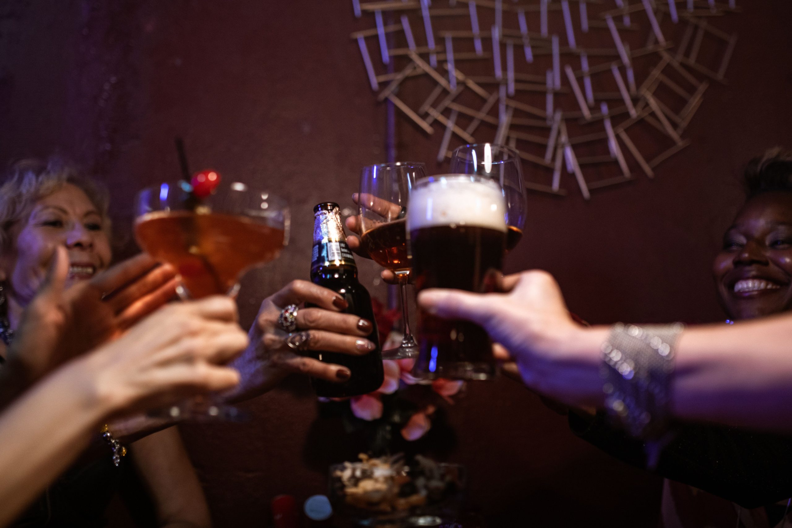 Pessoas em um pub brindando, cada um com uma cerveja de cor diferente.