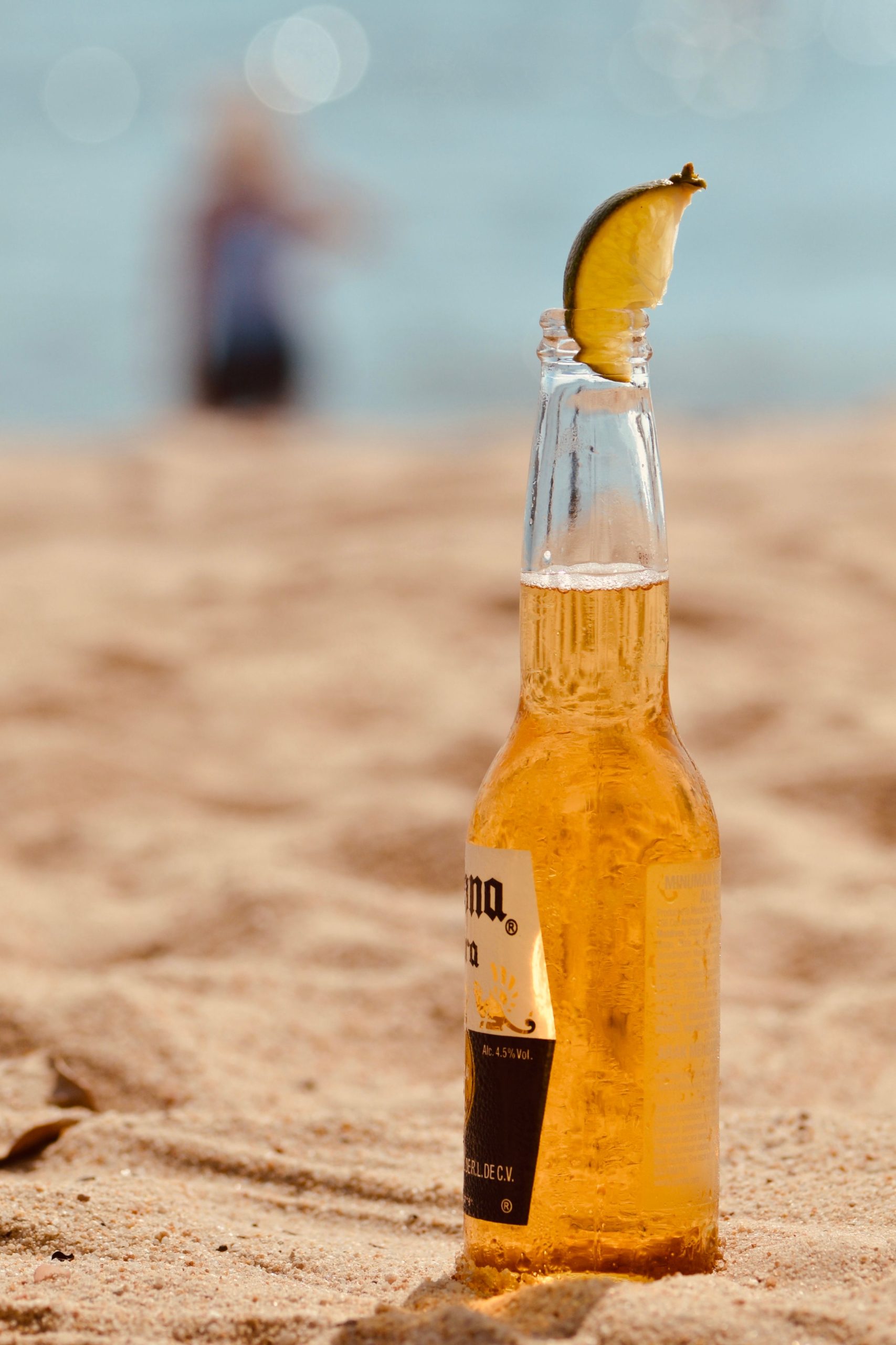 Imagem de uma corona com limão, na areia