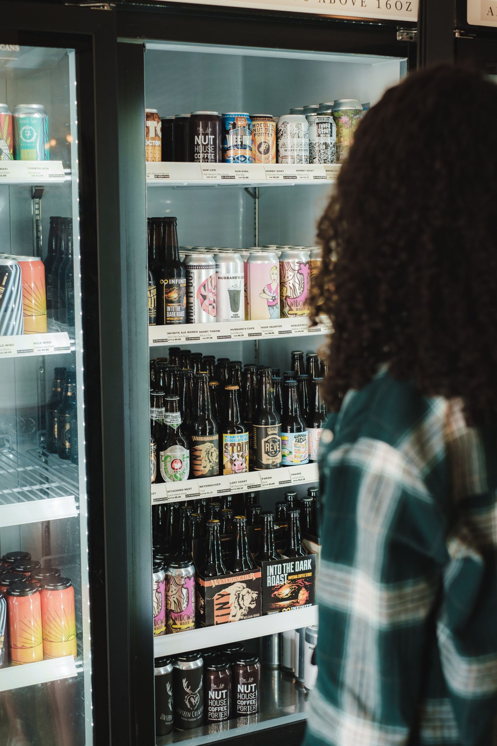 foto de menina olhando geladeira com diversos rótulos de cerveja diferentes